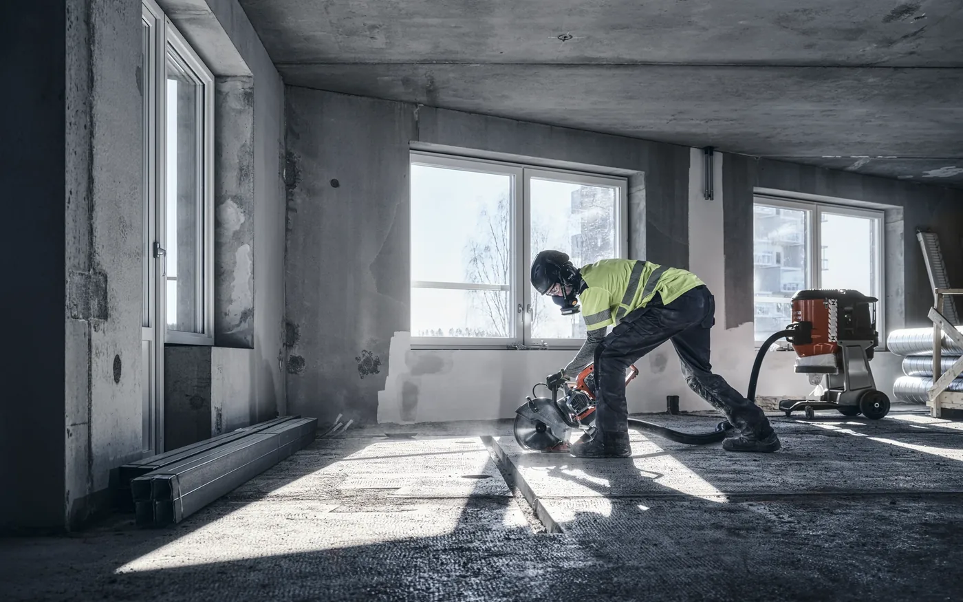 Operator cutting a concrete floor indoors with dust extraction connected